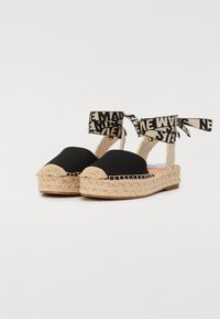 Sorte kanvas espadriller med en juteplattform, som har en vevd mellomsole og tekstilankeliv med et trykt design.