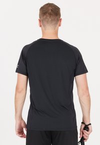 Svart atletisk T-shirt gjord av lättviktig tyg, med korta ärmar och en enkel, strömlinjeformad design med rund halsringning.