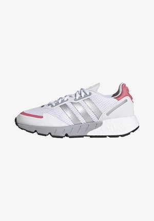 Zapatilla deportiva blanca con parte superior de malla, acentos grises, diseño de tres franjas plateadas, suela de goma texturizada y una pestaña en el talón de color rosa.