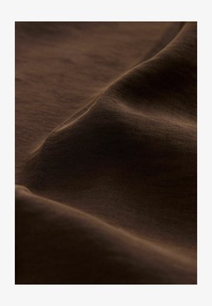 Pruun kangas, millel on sujuv tekstuur, esitleb peeneid laineid ja pehme läike. Materjalil on ühtlane välimus, millel on matt viimistlus.