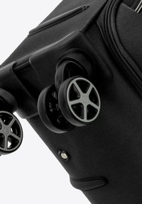 Valise noire à roulettes avec deux roues, accents gris, un extérieur texturé et une fermeture éclair lisse sur le compartiment principal.