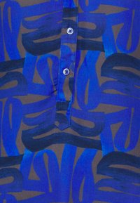 Blue patterned shirt featuring abstract brushstroke design in varying shades, with a button-down front and contrasting dark background.