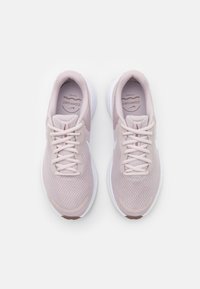 Baskets de sport rose clair avec une tige en mesh, semelle blanche rembourrée et lacets assortis. Bout arrondi et marquage subtil sur la semelle intérieure.