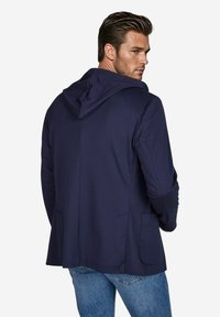 Marineblauwe hoodie-jack met een zachte textuur, iets getailleerd ontwerp, twee zijzakken en een rugpasdetail.