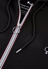 Schwarze Zip-Hoodie mit weißen und roten Akzentstreifen, silberner Reißverschlussbeschläge und einem kleinen weißen Baum-Logo auf der Brust. Weiche Stofftextur.