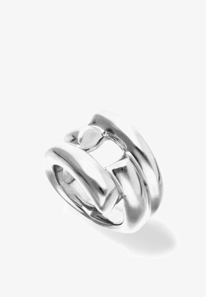 Bague argentée épaisse avec un design audacieux et abstrait, comportant de larges bandes lisses et courbées se chevauchant.