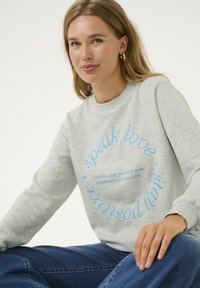 Šedá mikina s kulatým výstřihem a dlouhými rukávy, s modrým nápisem: "mluv lásku" a "zůstávej pozitivní." Měkká látka, uvolněný střih.