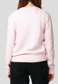 Maglione rosa chiaro lavorato a maglia con maniche lunghe, polsini e orlo a coste, caratterizzato da una texture liscia e un design classico con scollo rotondo.