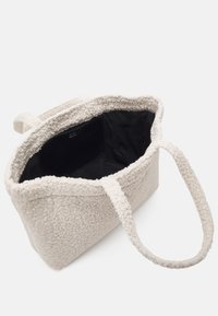 White, fluffy-textured tote bag with two sturdy handles. Black interior lining. Soft, structured shape with no visible closures.