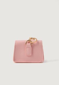 Petite pochette en cuir rose avec des anneaux en or attachés, bords cousus, sur un fond blanc uni.