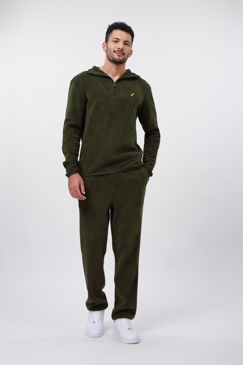 Maslinasto zeleni flis zip-hoodie s kengurutom džepom, uparen s odgovarajućim flis trenerkama. Bijele tenisice upotpunjuju odjevnu kombinaciju.