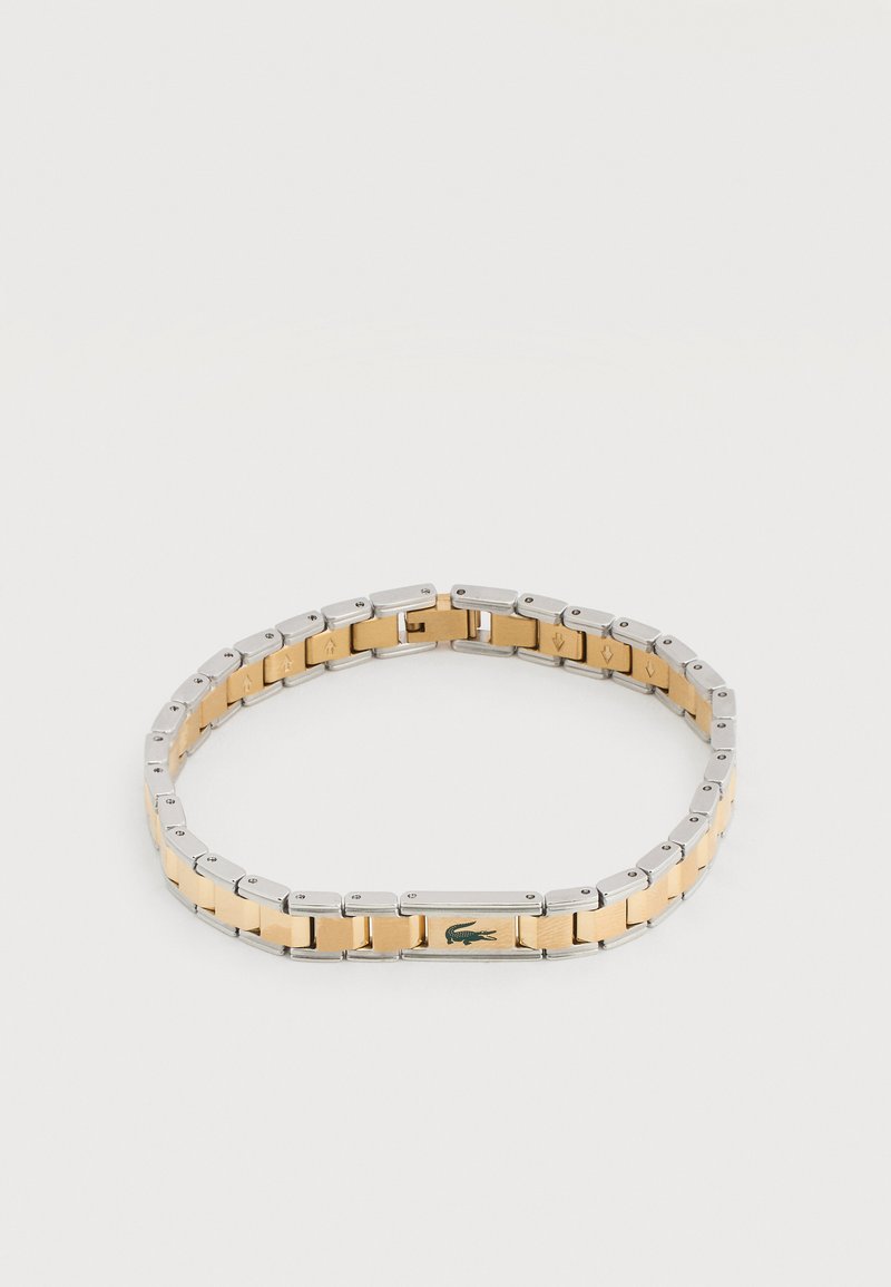Δίχρωμο μεταλλικό βραχιόλι με χρυσούς κεντρικούς κρίκους και ασημένιες άκρες, με μικρό πράσινο λογότυπο κροκοδείλου σε έναν χρυσό κρίκο.