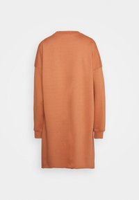 Dlouhé, př oversized pletené šaty v barvě rezavé. Vyrobeno z měkké, texturované tkaniny s dlouhými rukávy a kulatým výstřihem.