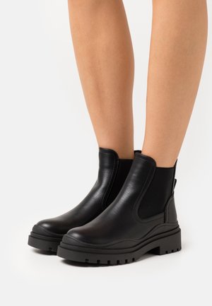 Bottines en cuir noir avec des panneaux latéraux élastiques, bout arrondi et semelle en caoutchouc texturée dotée de profondes rainures pour une adhérence et une stabilité accrues.