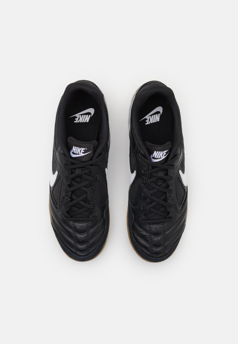 Baskets Nike noires avec un dessus en cuir texturé, un swoosh blanc, une languette en mesh noir et une semelle en caoutchouc beige. Design avec lacets et col rembourré.
