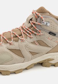 Beige vandringskänga med nät- och mockamaterial, utrustad med orange och grå flätade snören, en texturerad sula och formar för stöd.
