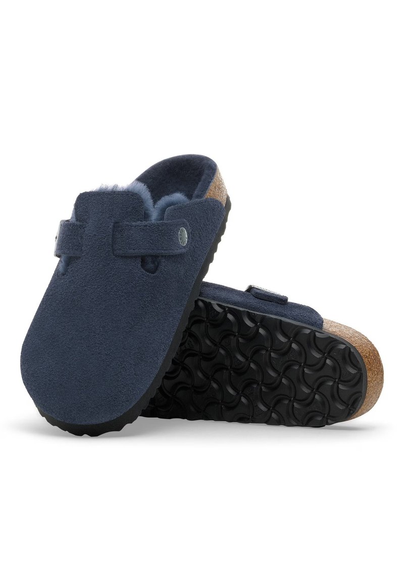 Navyblaue Wildlederclogs mit einem Pelzinnenfutter, Korkzwischensohle und strukturiertem schwarzen Gummiaußensohle. Verstellbarer Riemen mit Metallknopfdetail.
