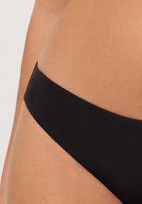 Czarny dół bikini o gładkiej fakturze, niskim kroju i minimalistycznym designie. Charakteryzuje się jednolitym kolorem, bez wzorów czy akcentów.