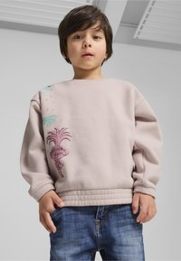 Helles rosa Sweatshirt mit einem Cartoon-Charakter, floralen Designs und gerippten Bündchen, kombiniert mit blauen Jeans.