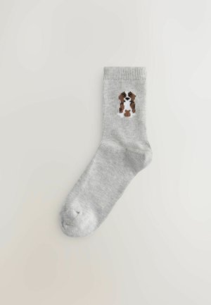 Gray cotton sock featuring a brown and white dog illustration on the outer side. Ribbed texture at the cuff. Classic ankle length.