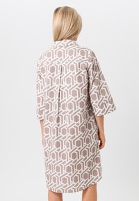 Robe de style kimono beige avec un motif géométrique blanc, des manches courtes et un dos plissé pour une meilleure circulation de l'air.