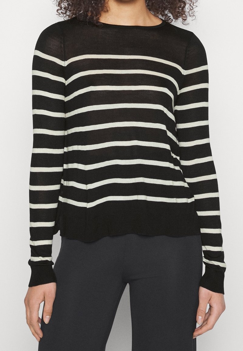 Pull léger à rayures noires et blanches, manches longues, encolure arrondie et ourlet légèrement asymétrique.