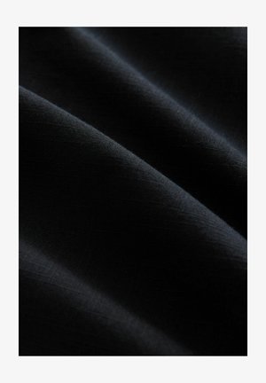 Tissu noir avec une texture lisse, présentant de légères reflets de lumière et un léger brillant, affichant des plis doux et fluides.