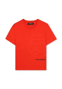 T-shirt en coton rouge avec un design minimaliste, comprenant un contour de visage en pointillé et le logo "KARL LAGERFELD" en noir. Manches courtes, col rond.