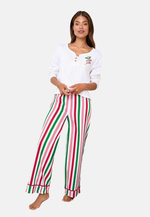 Bluză albă cu mânecă lungă, brodată cu textul „Holly Jolly” și nasturi roșii, purtată împreună cu pantaloni de pijama rai multicolori în nuanțe de roșu, verde și alb.