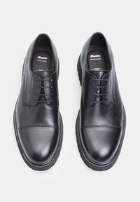 Scarpe in pelle nera con una texture liscia, punta tonda e quattro occhielli per i lacci. Presentano un delicato dettaglio di cucitura sulla parte anteriore.