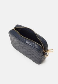 Piccola borsa in pelle intrecciata di colore blu navy con zip dorata parzialmente aperta, che mostra l'interno in tessuto scuro e il tirazip dorato con anello.
