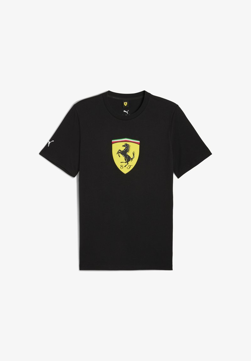 Melna T-kreklu ar dzelteno Ferrari logotipu, kas attēlo uzjautrīgu zirdziņu, balto PUMA logotipu uz vienas piedurknes un krāsainu robežu ap emblēmu.