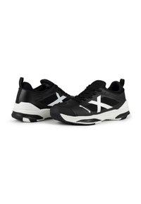 Scarpe sportive nere con accenti bianchi, con una parte superiore testurizzata, lacci e una suola ammortizzata, progettate per stabilità e comfort.