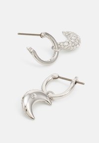 Boucles d'oreilles en argent en forme de croissant de lune poli, l'une étant ornée de strass pour un éclat et une texture supplémentaires.