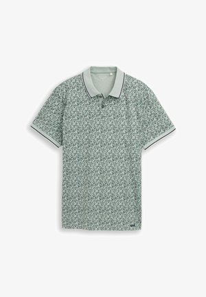 Polo à manches courtes vert clair avec imprimé floral noir et blanc, col et poignets de manches unis avec des rayures noires.