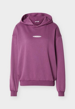 Vijolična dolga majica s kapuco z belim majhnim napisom na sprednji strani, rebrastimi robovi na rokavih in pasu, prikazana na ravni svetlo sivi podlagi.