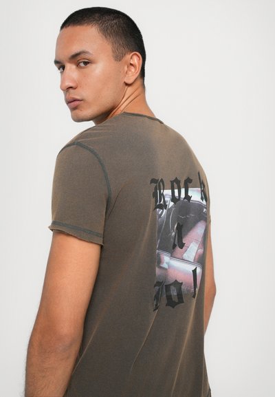 Olive green T-shirt with a round neckline, short sleeves, and a distressed texture. Features a graphic print with "ROCK" across the back.