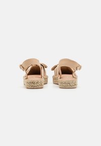 Light beige espadrille sandals with a textured fabric upper, woven jute sole, and adjustable ankle strap, featuring back bow accents.