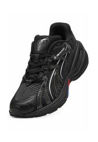 Chaussure de sport noire avec tige en mesh, design texturé et accents en plastique. Comprend des lacets et un détail de logo sur la languette.