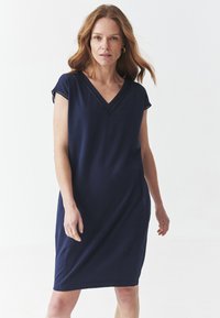 Robe V-nue bleue marine en tissu doux, dotée de manches courtes avec des détails en dentelle le long de l'ourlet. Coupe décontractée, longueur genou.