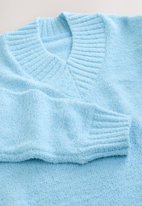 Hele sinine, tekstuuriga kampsun, millel on soonikuga V-kaelus ja mansetiga varrukad. Pehme, sametine kangas uduse väljanägemisega.