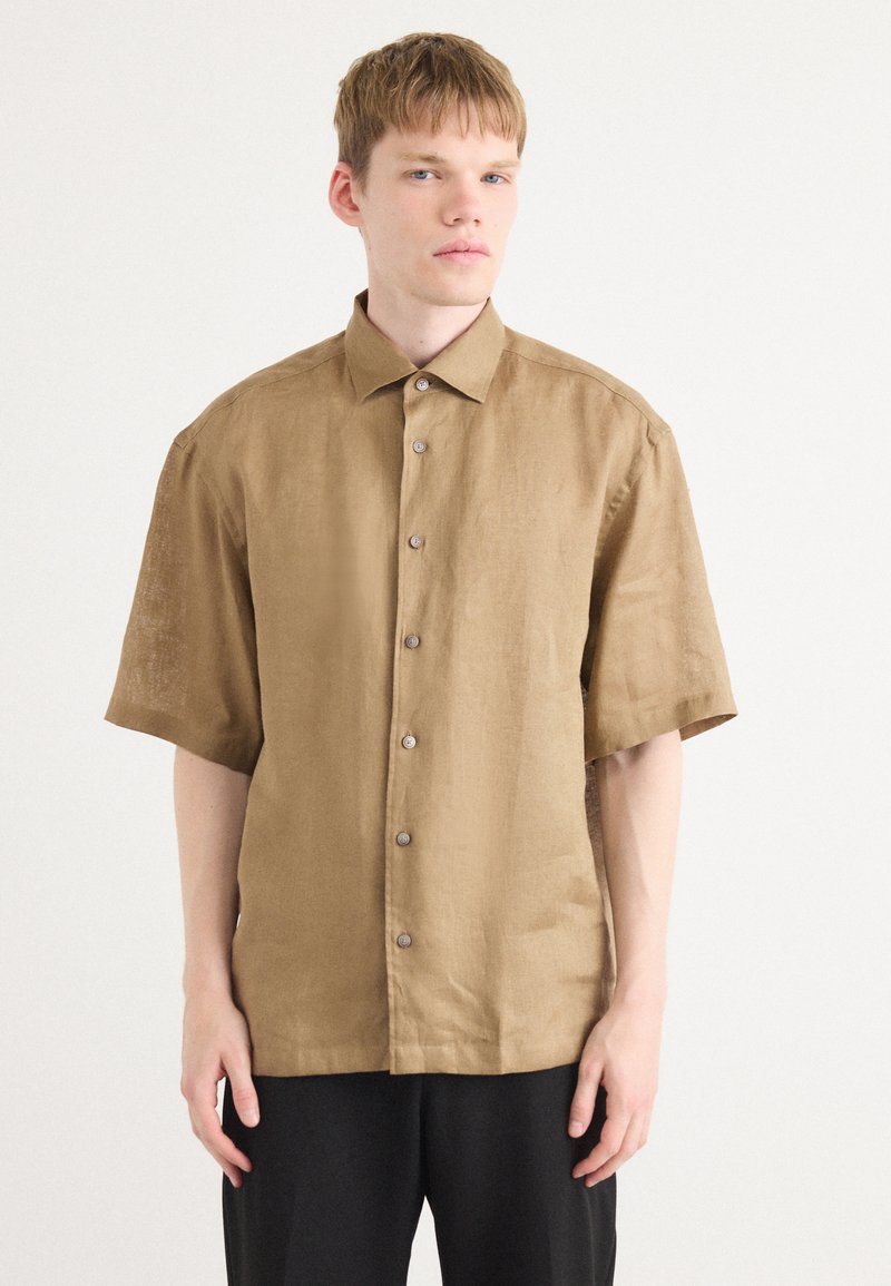 Korte mouwen, lichtbruine linnen blouse met een knoopsluiting aan de voorkant en een standaard kraag. Bevat zichtbare stiksels en bruine knopen.