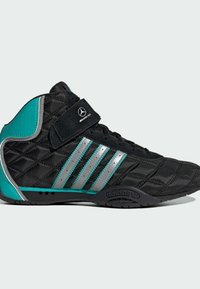 Chaussure de sport noire avec une texture matelassée, accents turquoise, logo trois bandes argentées et bride en Velcro. Semelle extérieure en caoutchouc pour une bonne adhérence.