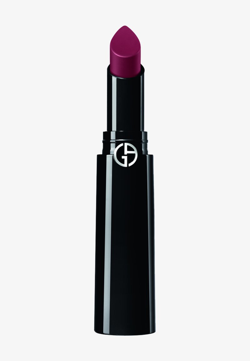 Étui cylindrique noir pour rouge à lèvres avec un raisin de rouge à lèvres violet profond et un logo circulaire argenté près du haut.