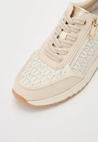 Baskets beiges avec un dessus à motif, en suède texturé, à lacets, avec un détail de fermeture éclair doré et une semelle en caoutchouc de couleur claire.