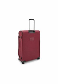 Red hard-shell suitcase with a textured finish, retractable handle, and four wheels for mobility. Features a reinforced base and side handles.