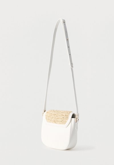 Λευκή τσάντα χιαστί με ρυθμιζόμενο λουρί και πλεκτή μπεζ λεπτομέρεια στην πτερυγίδα, εμφανιζόμενη πάνω σε απλό φωτεινό φόντο.