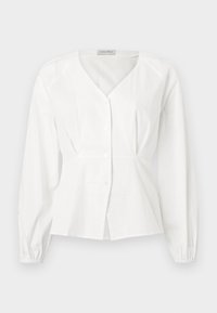 Blouse blanche à manches longues avec col en V, boutonnée à l'avant, taille cintrée et poignets élastiques, présentée sur un fond uni.