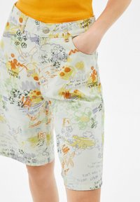 Pantalones cortos de textura ligera en tonos pastel con un patrón de garabatos coloridos que incluyen motivos florales y abstractos. Diseñados con bolsillos laterales y cierre de botones.