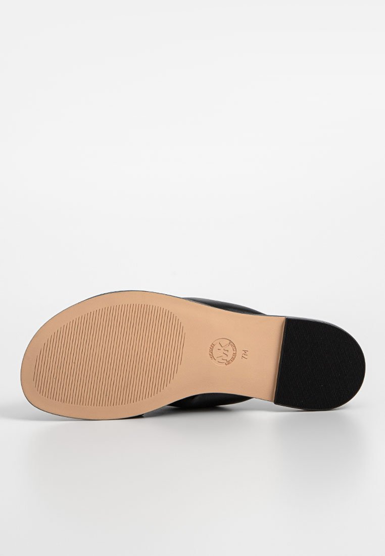 Semelle de chaussure noire avec un fond en caoutchouc beige lisse, présentant des rainures pour une meilleure adhérence et un logo circulaire. La forme est arrondie au niveau des orteils et du talon.